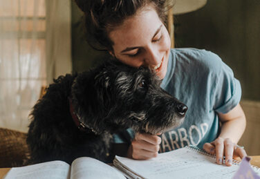 dog comforts girl doing homework