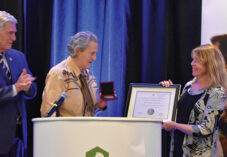 Susan Milward awards Dr. Temple Grandin on stage with plaque
