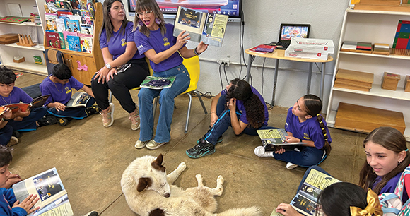 teacher reads book to circle of children in classroom