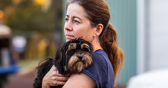 woman holds small dog solemnly
