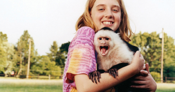 girl holds monkey in a suburban park
