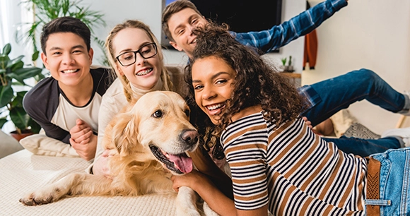 a happy Golden Retriever posing with a playful group of teenagers