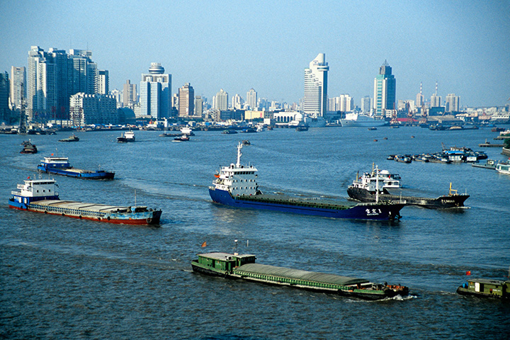 a city skyline stands behind a waterway full of boats