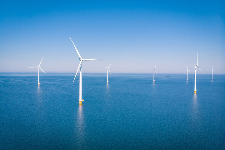 windmills stand in the ocean on an offshore wind farm