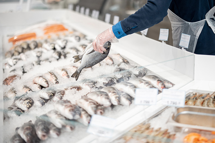 a hand adds two dead fish to a full cooler