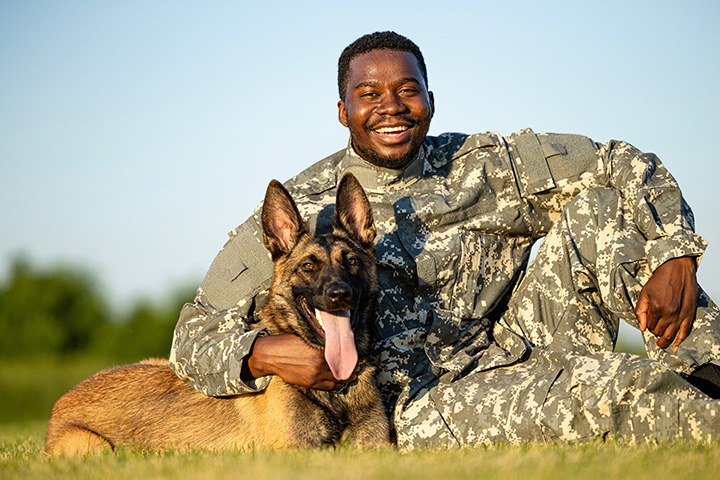 smiling soldier hugging canine armed forces member with tongue out